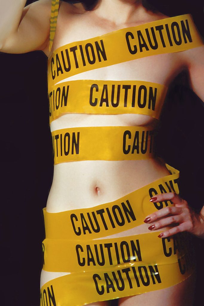 Woman wearing only yellow CAUTION tape